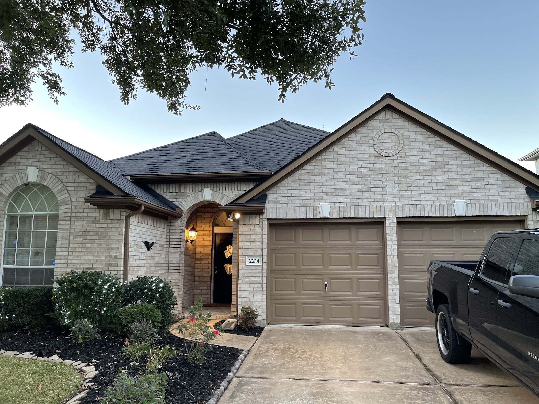 Completed dark shingle roof on single-story brick home photographed at dusk