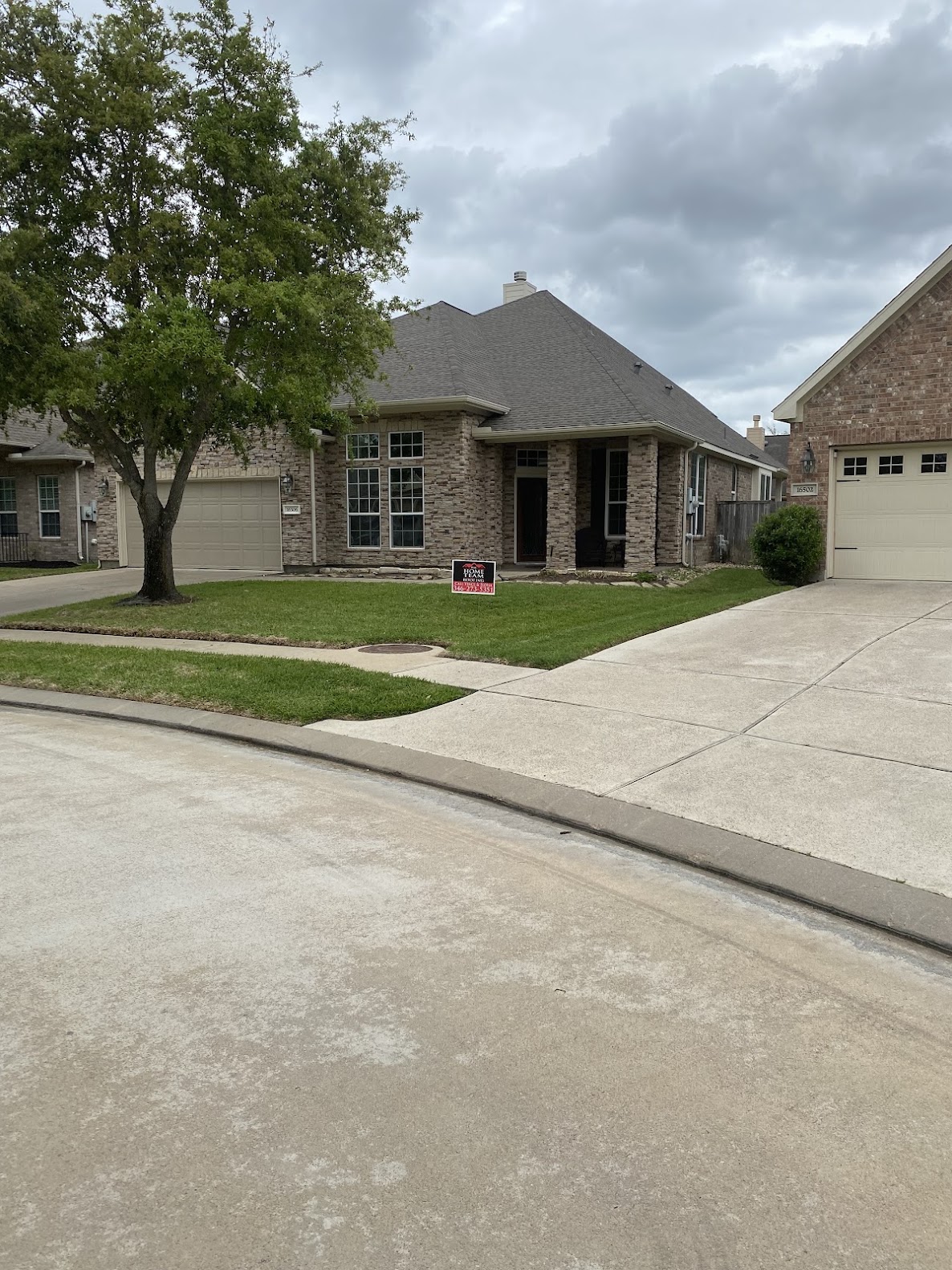 Completed residential shingle roof on brick home viewed from street
