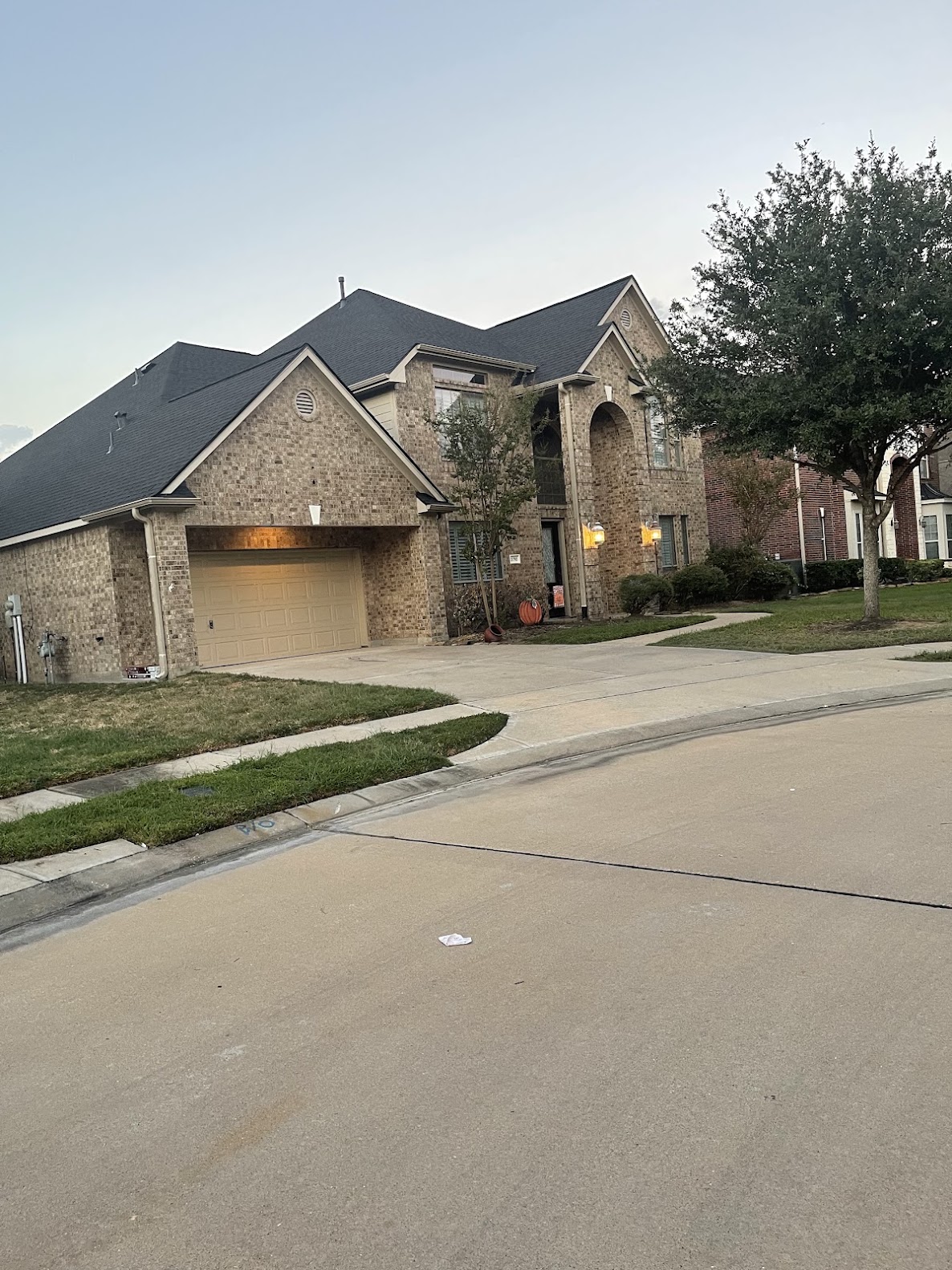 Completed dark shingle roof on two-story brick home photographed at dusk