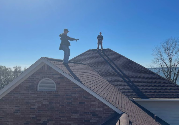Home Team roofing crew standing on a completed grey shingle roof
