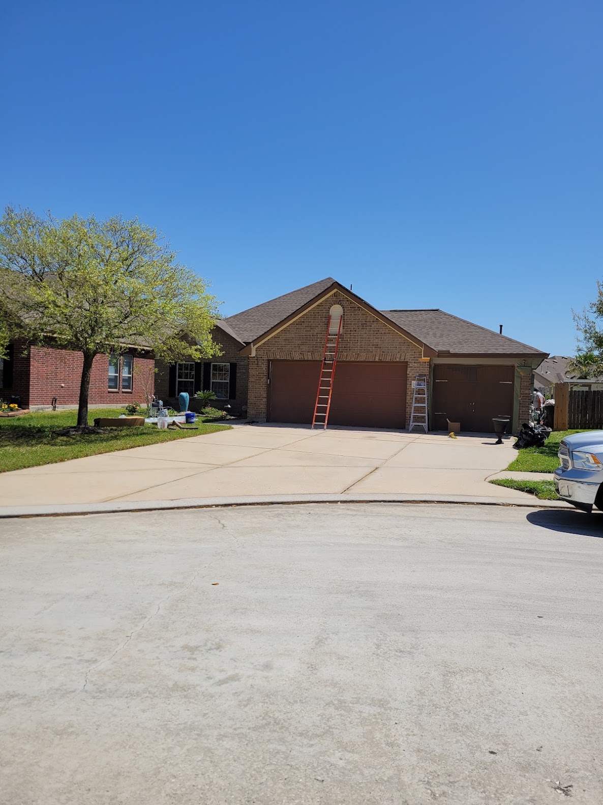 Residential roof installation with ladder visible at single-story brick home