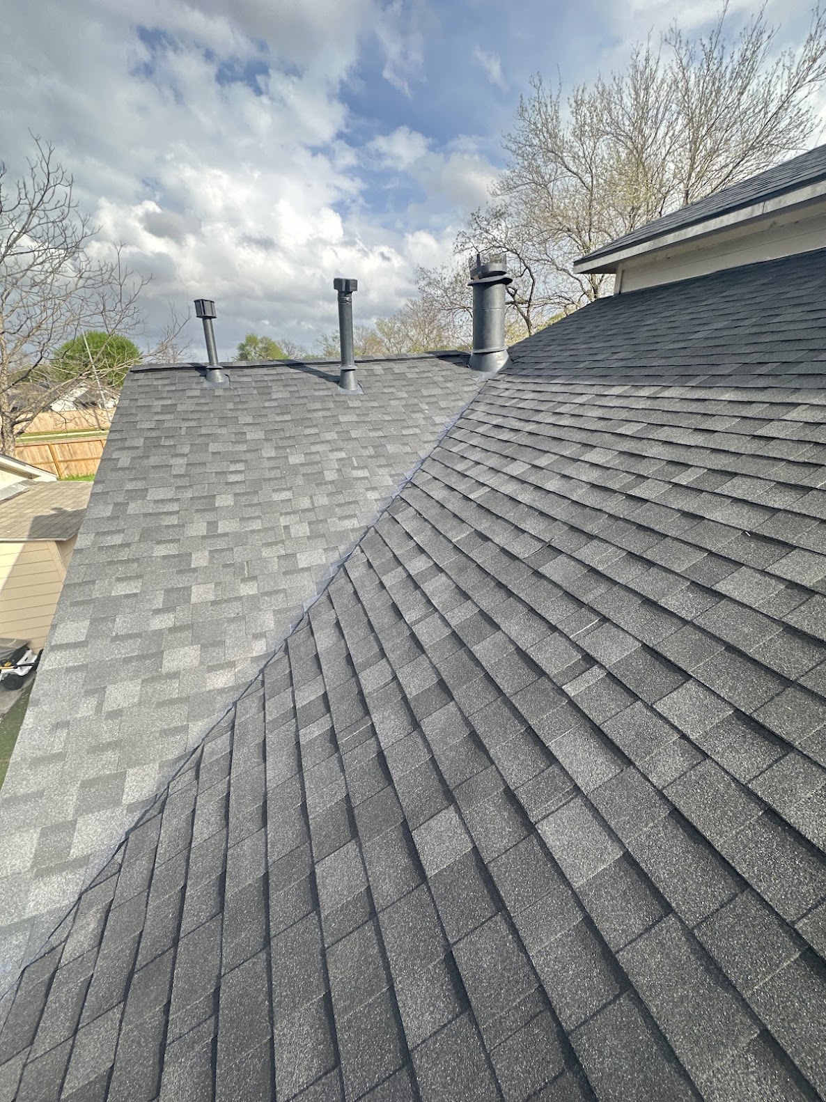 Close-up detail of completed grey shingle roof with multiple roof planes